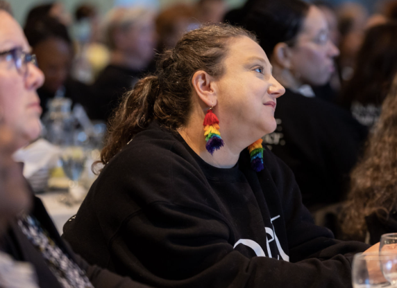 Woman with rainbow earrings looking ahead at the 2022 Rockstar Woman Brunch