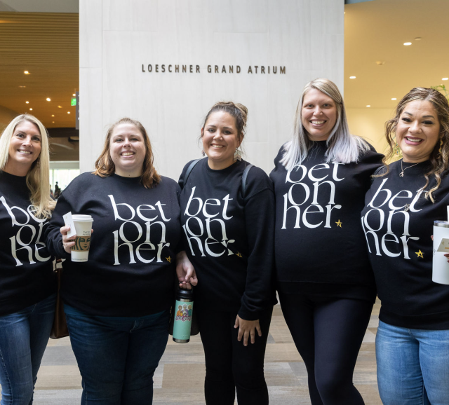 Five ladies wearing "bet On Her" sweaters posing for a picture.