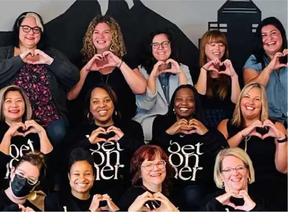 Ladies posing with hands in shape of hearts.
